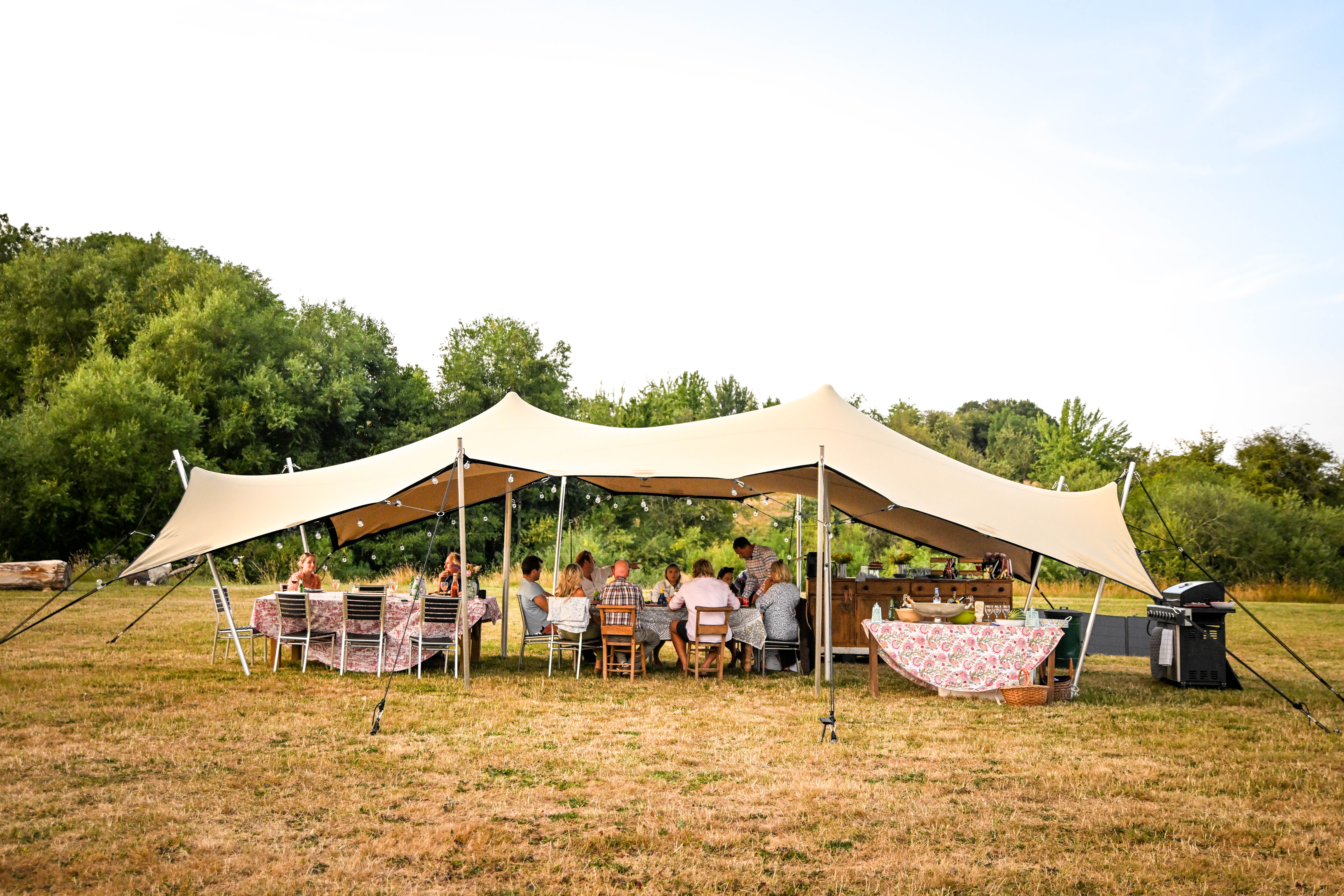 Group dining under the stretch tent at Hopnest glamping retreat